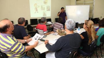 professor dá aula e alunos sentados observam #paratodosverem