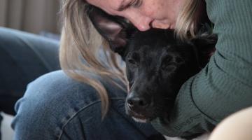 mulher abraça e beija cão na cabeça. Os dois estão de olhos fechados. #paratodosverem