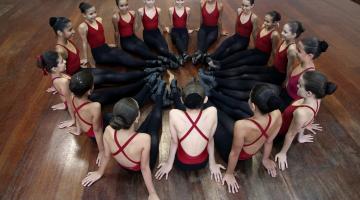 bailarinas sentadas em circulo no palco #paratodosverem