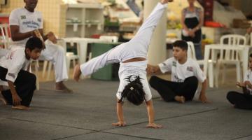 menina dá pirueta durante aula de capoeira #paratodosverem