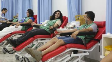 agentes de combate a endemias uniformizados estão em macas doando sangue. Na imagem se vê quatro doadoras e uma mulher atendendo um deles. #paratodosverem 