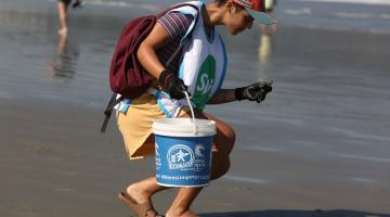 pessoa retira lixo da praia #paratodosverem 
