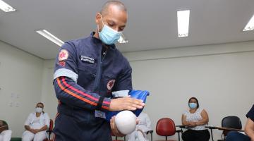 técnico mostra técnica em boneco, observado por enfermeiras #paratodosverem 