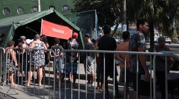 pessoas formam fila diante de tenda para receber atendimento. #paratodosverem 