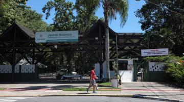 a fachada do Jardim Botânico com uma pessoa passando na calçada. #paratodosverem