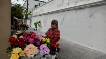 mulher vende flores e ao fundo operários pintam muros #paratodosverem