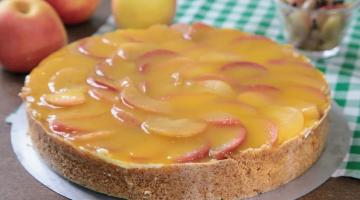torta de mação sobre uma mesa com maçãs in natura ao fundo. #paratodosverem 