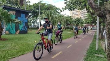 Pessoas andando de bicicleta na ciclovia da praia #paratodosverem