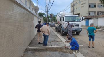 homens trabalham na construção de calçadas. Há um caminhhão de concreto parado na rua. #paratodosverem 