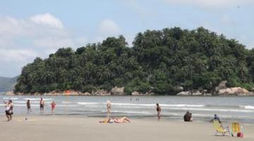Ilha Urubuqueçaba ao fundo com banhistas e cadeiras na faixa de areia em frente. #paratodosverem