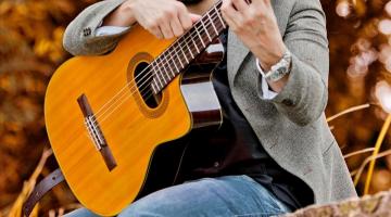 leandro ramajo posa para foto sentado segurando violão. #paratodosverem 