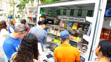 estande do projeto com vários livros dispostos e pessoas em torno. #paratodosverem