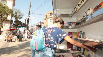 mulher pega livros no estande #paratodosverem 