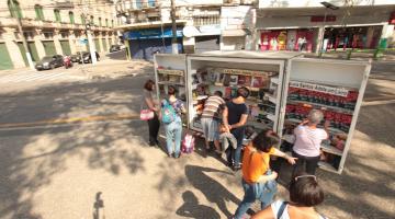 pessoas pegando livros no estande #paratodosverem 