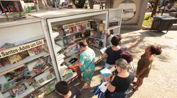 pessoas olhando o estande com livros #paratodosverem 