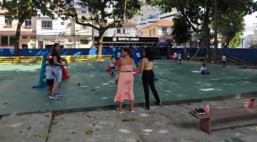 pessoas estão em parque infantil com piso recém-pintado de verde. #paratodosverem