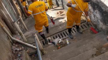 Homens limpando escadaria em morro. #paratodosverem