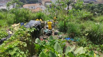 Homens realizam limpeza em meio a vegetação no morro #paratodosverem