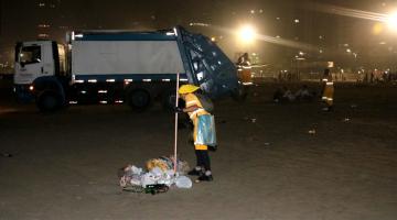 Profissionais de limpeza recolhem lixo na faixa de areia. #paratodosverem