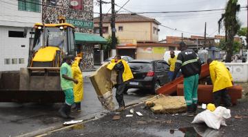 funcionários recolhem colchão e móveis em área próximo a um canal. #paratodosverem