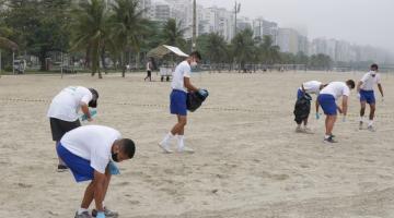 Jovens recolhem lixo na areia da praia #paratodosverem
