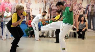 Um jovem e uma idosa praticam capoeira #paratodosverem