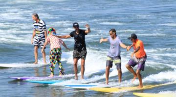 pessoas surfando em longboards #paratodosverem