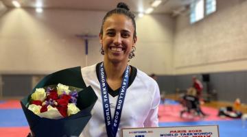 Gabriele exibe premiação e flores com medalha no peito. #paratodosverem