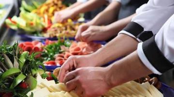 Bancada com vários alimentos. Mãos, em close,manipulam frutas. #Pracegover