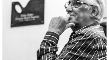 Maestro Manzione de perfil com a mão apoiada no queixo. #pracegover