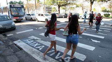 Pedestres atravessam em faixa com a inscrição faixa viva #pracegover 