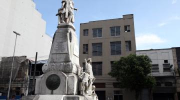 fachada do prédio com estátua e praça em primeiro plano #pracegover 