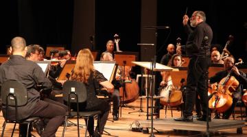 músicos de orquestra com maestro à frente. #paratodosverem 