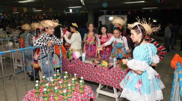 Adolescentes disputam jogo de argolas. Eles estão vestidos com roupas típicas. #paratodosverem