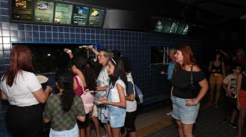 pessoas olham tanque do aquário #paratodosverem 