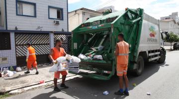 Coletores removem lixo reciclável de rua e depositam em caminhão basculante. #Pracegover