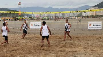 jogo de futevôlei nas areias da praia com dois atletas de cada lado da rede. #paratodosverem