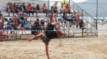 atleta dá voadora na bola durante jogo de futevôlei #paratodosverem