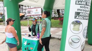 pessoa conversa com agentes em estande da dengue #paratodosverem