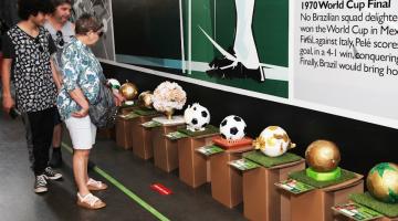 pessoas olham bolas em exposição #paratodosverem