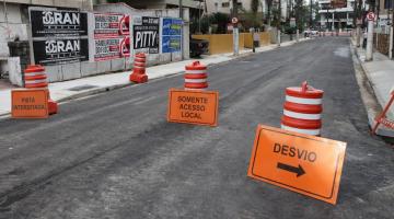 rua está recém-asfaltada. cones em primeiro plano informam sobre acesso local. #paratodosverem 