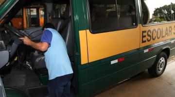 homem está mexendo em banco de condução escolar que está parada. #paratodosverem 