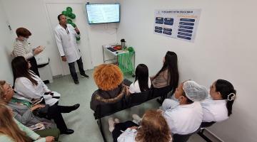 enfermeiro em pé fala a profissionais de saúde sentados. #paratodosverem