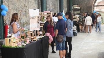 pessoas observam artigos à venda na feira feito em santos #paratodosverem