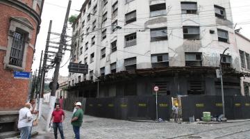 vista geral do prédio com tapume pelo térreo. Homens trabalhando na entrada. #paratodosverem