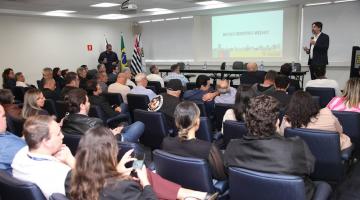 pessoas sentadas em auditório assistem palestra. #paratodosverem
