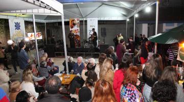 músicos cantam em palco com plateia ao fundo. #paratodosverem