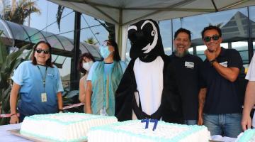 pinguim e pessoas na frente do bolo de aniversário #paratodosverem