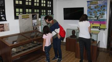 duas mulheres e uma criança observam artefatos da exposição #paratodosverem