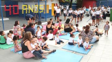 alunos e adultos reunidos em pátio assistindo apresentação de banda. #paratodosverem